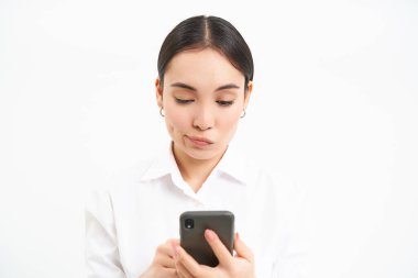 Endişeli yüzlü Koreli iş kadını portresi, cep telefonu ekranında mesaj okuyor, beyaz ekranda izole edilmiş..