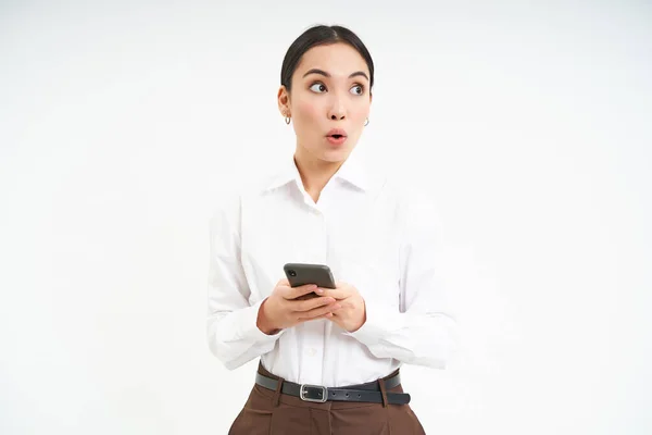 stock image Portrait of businesswoman, asian saleswoman with smartphone, looks aside at banner, promotion text on right side, isolated on white background.