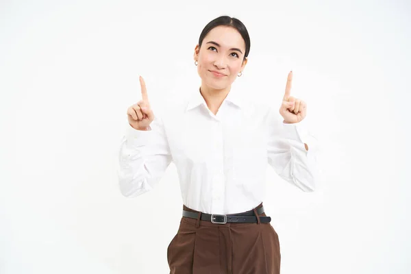 stock image Image of female entrepreneur, points fingers up, shows advertisement on top, smiles with pleased face, white background.