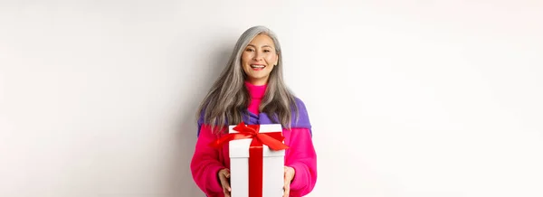 美丽的亚洲老年妇女笑着祝贺情人节 把礼物放在盒子里 站在白色的背景上 — 图库照片