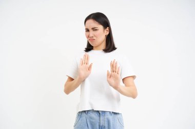 Tiksinç kız bir şeyi reddediyor, hoşlanmadığını ve nefret ettiğini gösteriyor, beyaz arka planda duruyor..