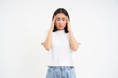 Üzgün kadın el ele tutuşuyor, baş ağrısı çekiyor, migreni var, başı dönüyor, beyaz arka planda duruyor..