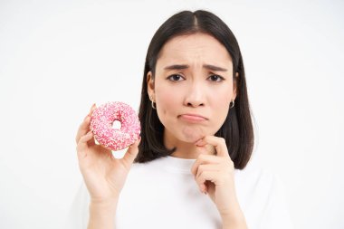 Üzgün tatlı kıza yakın, lezzetli jöleli donut gösteriyor, diyet yapıyor, lezzetli çörek yiyemiyor, abur cubur yiyemiyor..