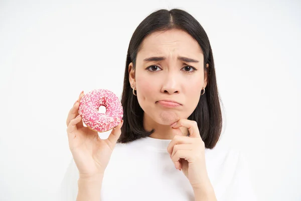 stock image Close up of sad cute girl, shows tasty glazed doughnut, being on diet, cant try delicious donnut, junk food concept.