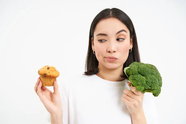 Portrait Asian Girl Thinking What Eat Choosing Cupcake Broccoli Vegetables Royalty Free Stock Images