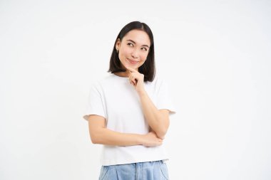 Asyalı kadın düşünüyor, gülümsüyor memnun, bir şey üzerinde düşünüyor ve karar veriyor, beyaz stüdyo geçmişi.