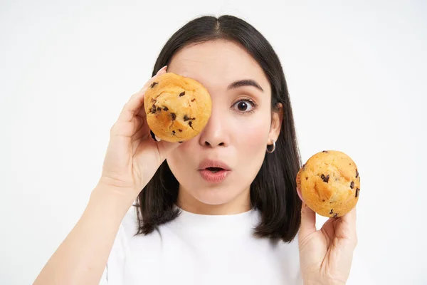 stock image Close up portrait of smiling korean woman, shows tasty cupcakes, eating cake and looking happy, pastry and bakery concept.