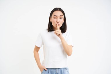 Kız portresi, şşşş hareketi, sessizce konuşur, bir şey söylemek için tabu, bir sır söyler, beyaz arka planda durur..