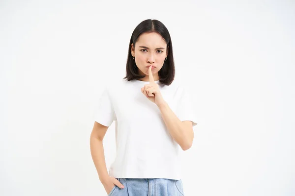 stock image Portrait of girl shushes, shhh gesture, speaks silently, taboo to say something, tells secret, stands over white background.