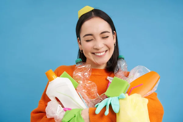 stock image Portrait of smiling asian woman with plastic garbage, holding waste and looks happy, collects litter for recycling center, sustainable lifestyle concept.