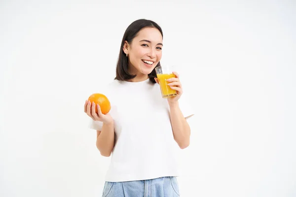 stock image Healthy smiling korean girl, drinks fresh juice squeezed from oranges, stays healthy, has normal diet, white background.