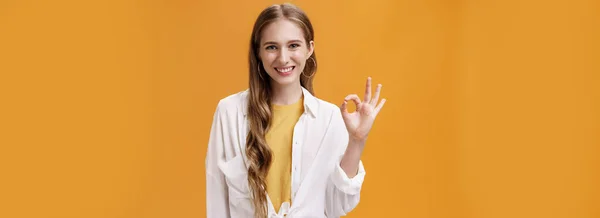 大丈夫よ フレンドリーで快適な笑顔の女の子とともに波状の髪で流行のブラウスオーバーTシャツショーOkまたは完璧なジェスチャー笑顔積極的かつ保証された肯定的な答え上のオレンジ壁 — ストック写真