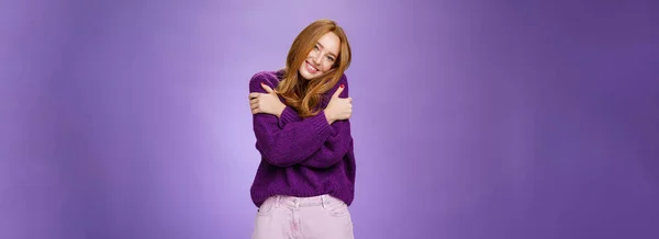 ライフスタイル 紫のセーターを身に着けている暖かさを感じながら肩にもたれて20代の愚かでかわいい屈託のない赤毛の女性は バイオレットの壁の上に居心地の良いリラックスした雰囲気の中で幅広く笑顔 — ストック写真