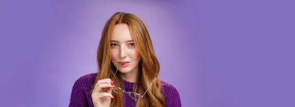スマートで創造的な女性の赤毛の天才のクローズアップショットは 眼鏡のフレームをかむとアイデアを持っているとしてカメラで好奇心を細めて 紫の背景に対して計画を立てます — ストック写真