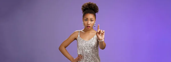 stock image Concerned worried young african-american woman in trendy dress extend index finger nervously look camera shushing prohibiting tell anyone secret frowning afraid, saying taboo, blue background.