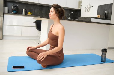 Sağlıklı genç bir kadın pilates yoga egzersizi yapıyor. İç kısımda antrenman yapıyor. Savaşçı pozunda duruyor. Beden ve zihin rahatlaması için fiziksel aktivite, sağlıklı yaşam tarzı konsepti..
