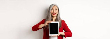İş için. Şaşırmış Asyalı kadın yönetici boş dijital tablet ekranı gösteriyor, kaşlarını kaldırıyor ve soluk soluğa kalıyorlar, beyaz arka planda duruyorlar..