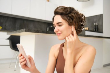 Genç fitness eğitmenini kapatın. Sağlıklı ve zinde bir kadın. Akıllı telefon, kablosuz kulaklık..