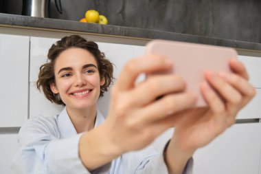 Mutlu, güzel bir kadının portresi akıllı telefondan selfie çeker, elini cep telefonuyla uzatır ve kendi fotoğrafını çeker, cep telefonuyla video kaydını kaydeder..