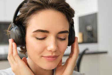 Kadın yüzünün yakın portresi, kablosuz kulaklıklarıyla müzik dinliyor, kulaklıklarda iyi ses kalitesinin keyfini çıkarıyor..