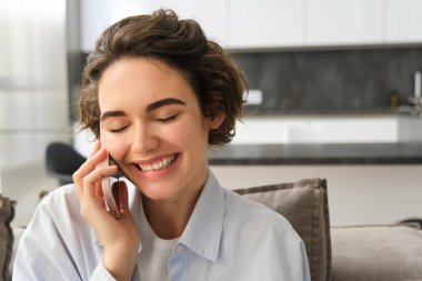 Mutlu, gülümseyen güzel bir kadının yakın portresi telefonla gülüyor, birini arıyor, cep telefonuyla komik bir konuşma yapıyor, arkadaşıyla konuşmak için akıllı telefonu kullanıyor..