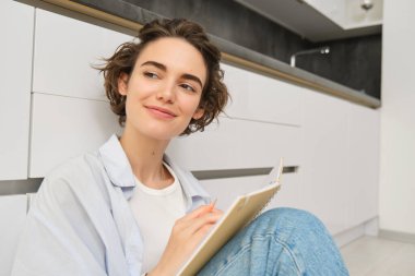 Yaratıcı genç bir kadın, notlar alıyor, evde oturuyor, düşüncelerini kağıda döküyor, ödevlerini yapıyor. İnsanlar, yaşam tarzı ve hobiler