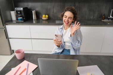 Geveze esmer kadın evde oturur, arkadaşıyla görüntülü sohbetler yapar, kameraya el sallar, akıllı telefonu tutar ve dizüstü bilgisayar kullanır..