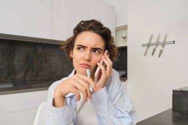 Kafası karışmış bir kadın görüntüsü, telefona cevap veren, kafası karışmış, konuşmayı anlamayan, akıllı telefon kullanan..