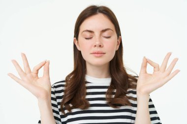 Her şey kontrol altında. Meditasyon yapan genç bir kadın, zen 'de duruyor, yoga pozu, sakin duruyor, kapalı gözlerle poz veriyor, rahat, düşünceli bir ifadeyle nefes alıyor..