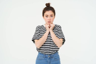 Şefkatli genç bir kadının portresi, sempati ile bakıyor, kameraya bakıyor, kaşlarını kaldırıyor, beyaz arka planda duruyor..