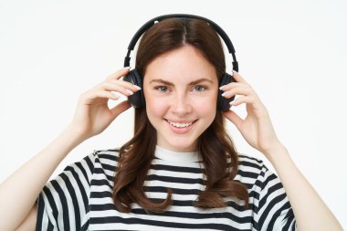 Kablosuz kulaklıkla güzel bir kadının portresi, müzik dinlemek, kulaklık kullanmak, kameraya gülümsemek, beyaz arka planda durmak..