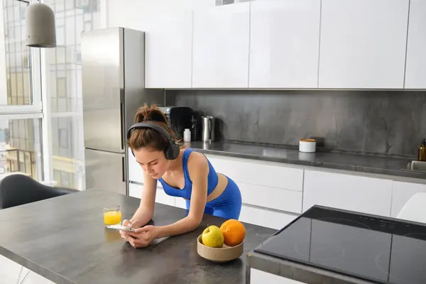 Retrato Mujer Morena Ropa Deportiva Usando Smartphone Pie Cocina Bebiendo —  Fotos de Stock