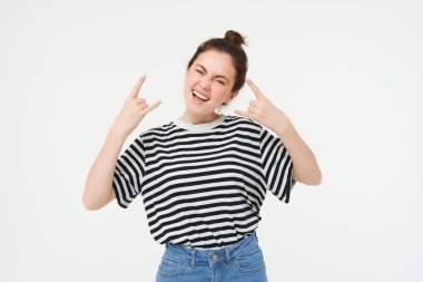 Heyecanlı genç bir kadının portresi eğleniyor, rock 'n roll yapıyor, konserden hoşlanıyor, neşeli poz veriyor, beyaz arka planda duruyor..