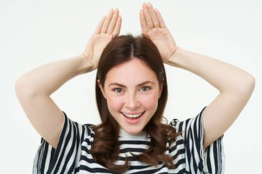 Sevimli esmer kız görüntüsü hayvanların ellerini başının üstüne koyup yediğini gösteriyor, gülümsüyor ve mutlu görünüyor, beyaz arka plan..