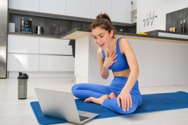 Formda olmanın portresi, gülümseyen fitness eğitmeni, dizüstü bilgisayarla konuşan kadın, müşteriyle egzersiz tartışması, görüntülü sohbet yoluyla online yoga dersi vermek..