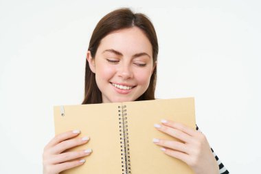 Genç bir kadının portresi ajandasına notlar yazar, günlüğüne yazar, ajandasına bakar, ajandasını elinde tutar, beyaz arka planda durur..