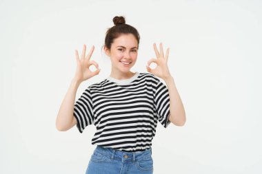 Mükemmel seçim. Gülümseyen stil sahibi genç bayan, tamam, tamam jest, sıfır işaret, beyaz arka plan üzerinde duran.