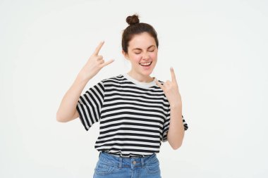 Çekici, kaygısız dans eden, heavy metal gösteren, jest üzerine rock yapan, beyaz arka planda duran kadın portresi..