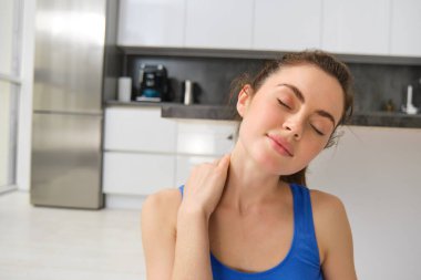Spor salonundaki yakın çekim kadın, antrenman, evden antrenman, boyun masajı, oturma odasında egzersiz. Spor ve refah kavramı