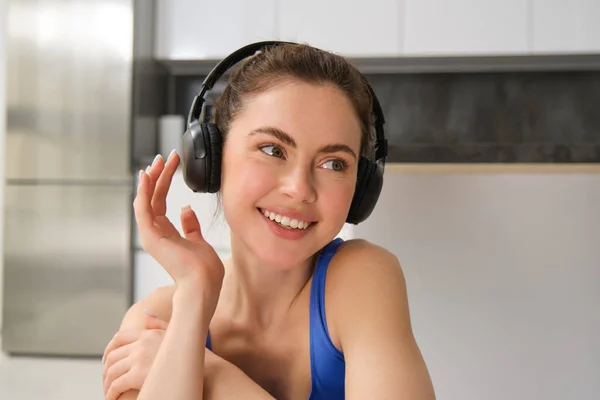 Close up portrait of attractive young smiling woman, workout, doing fitness training, listening music in headphones. Fitness and wellbeing concept