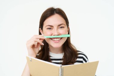 Güzel bir genç kadın resmi, elinde defter tutan öğrenci, not defteri ve kalem, gülümseyen ve mutlu görünen, beyaz arka planda soyutlanmış..