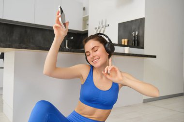 Kablosuz kulaklıkla genç bir kadının portresi, evden antrenman, spor yapmak, müzik dinlemek ve spor yapmak..
