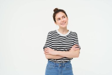 Gülümseyen bir kadının portresi, göğsünde çapraz kollar, düşünceli bir yüzle yana bakıyor, düşünüyor, seçim yapıyor, bir şeyler hayal ediyor, beyaz arka planda duruyor..