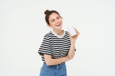 Sağlık ve refah hizmetleri. Elinde vitamin, beslenme takviyeleri, iyi cilt ve saçlar için tedavi, beyaz arka planda duran şişe tutan genç bir kadın..