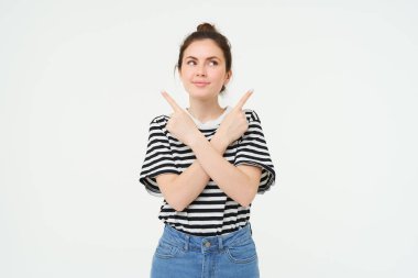 Güzel, gülümseyen, kafası karışmış genç bir kadının portresi, neyi seçeceğine karar verir, sağa sola, beyaz arka planda durur..