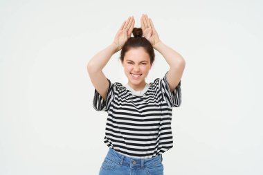 Kafasının üstünde tavşan kulakları gösteren güzel, mutlu genç bir kadın resmi. Heyecanlı görünüyor, beyaz arka planda poz veriyor. Yaşam tarzı ve insan kavramı