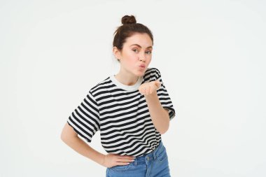 Güzel bir genç kadının portresi, hava öpücüğü verir, kameraya mwah gönderir, beyaz arka planda sevimli poz verir. Yaşam tarzı ve insan kavramı.