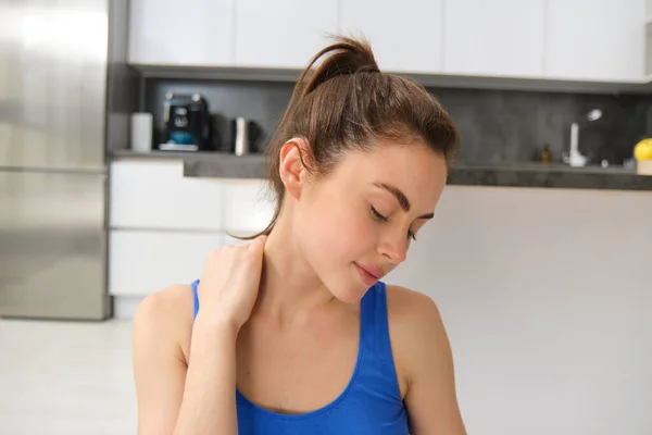 Image of woman workout at home, stretching her head and neck, does warm-up exercises before yoga, fitness training in living room.