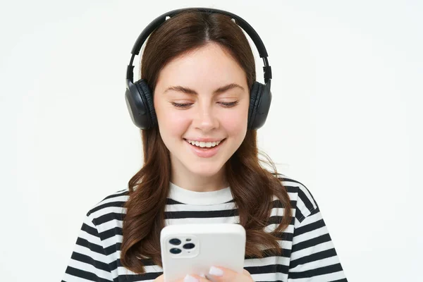 在耳机里的年轻女性形象 使用智能手机和笑 在手机上观看视频 在流媒体服务应用程序上听音乐 白色背景 — 图库照片