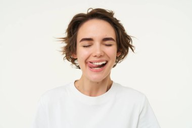 Mutlu, gülümseyen bir kadına yakın, beyaz dişlerini yalıyor, diş tedavisinden sonra mutlu hissediyor, stüdyo arka planında izole edilmiş..